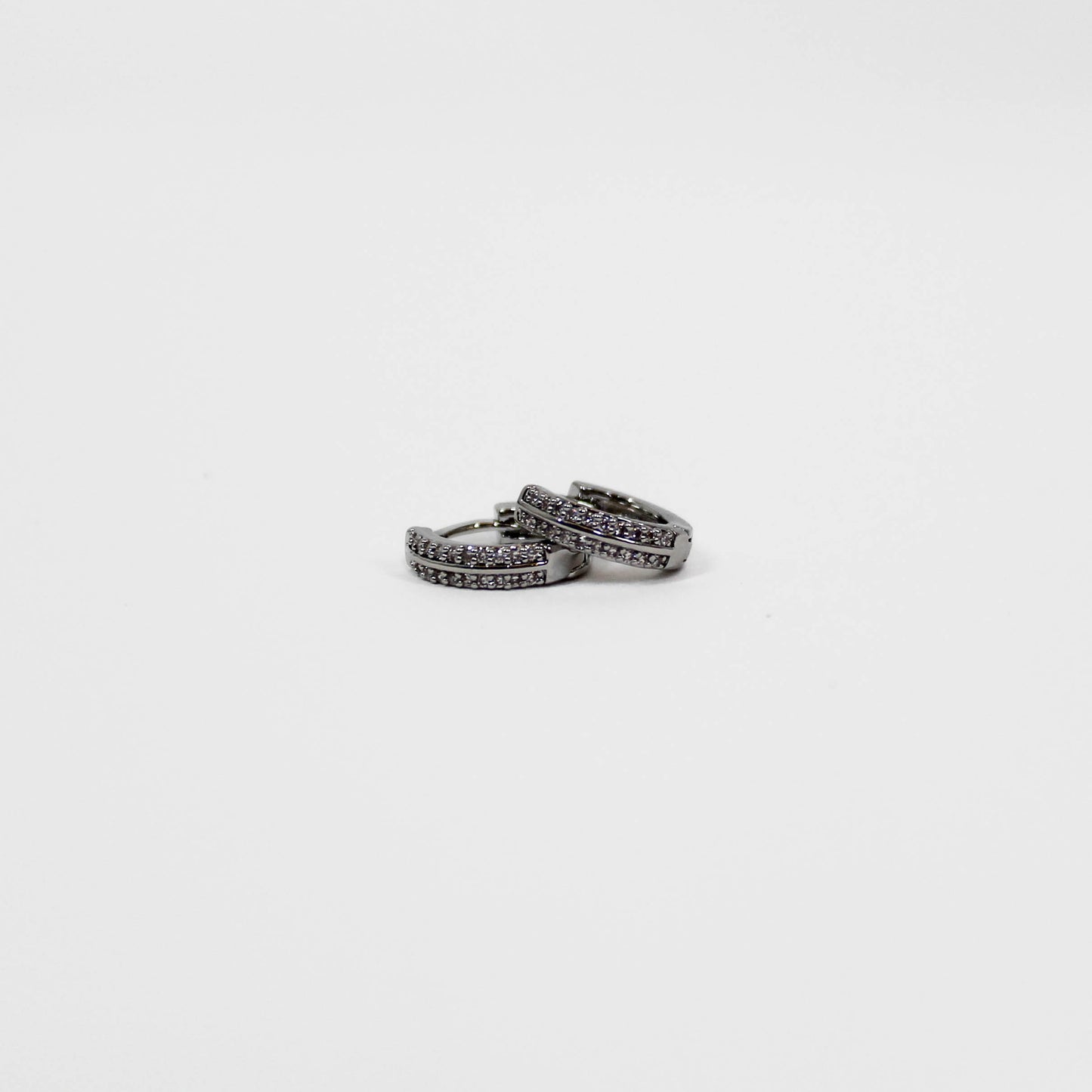 silver huggie hoop earrings on a white background