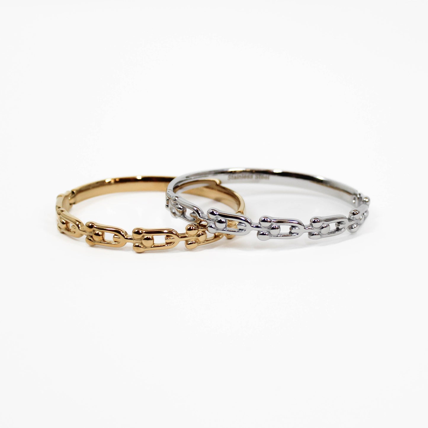 Two chain-link industrial link hinged bangle bracelets, one gold and one silver, on a white background.