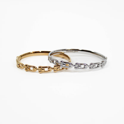 Two chain-link industrial link hinged bangle bracelets, one gold and one silver, on a white background.