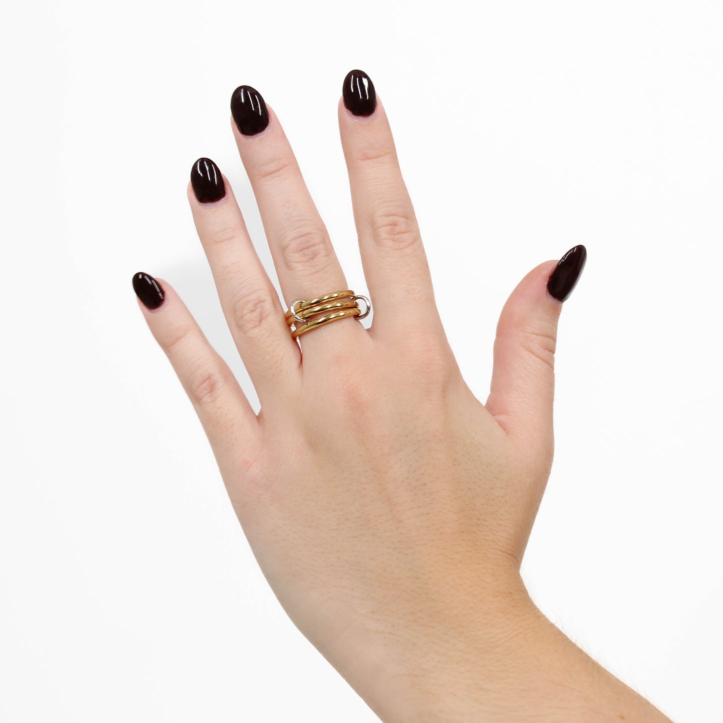 Hand wearing a gold interlocking link ring on a white background
