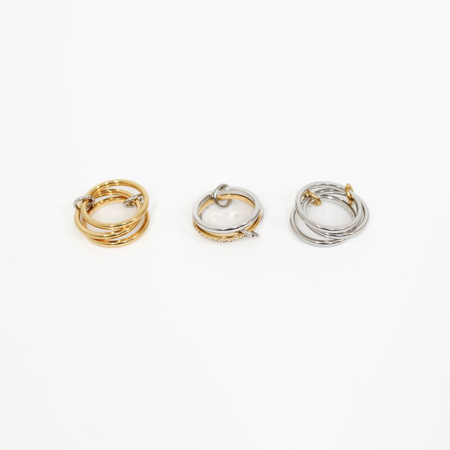 Three interlocking rings in gold, silver, and mixed metal on a white background