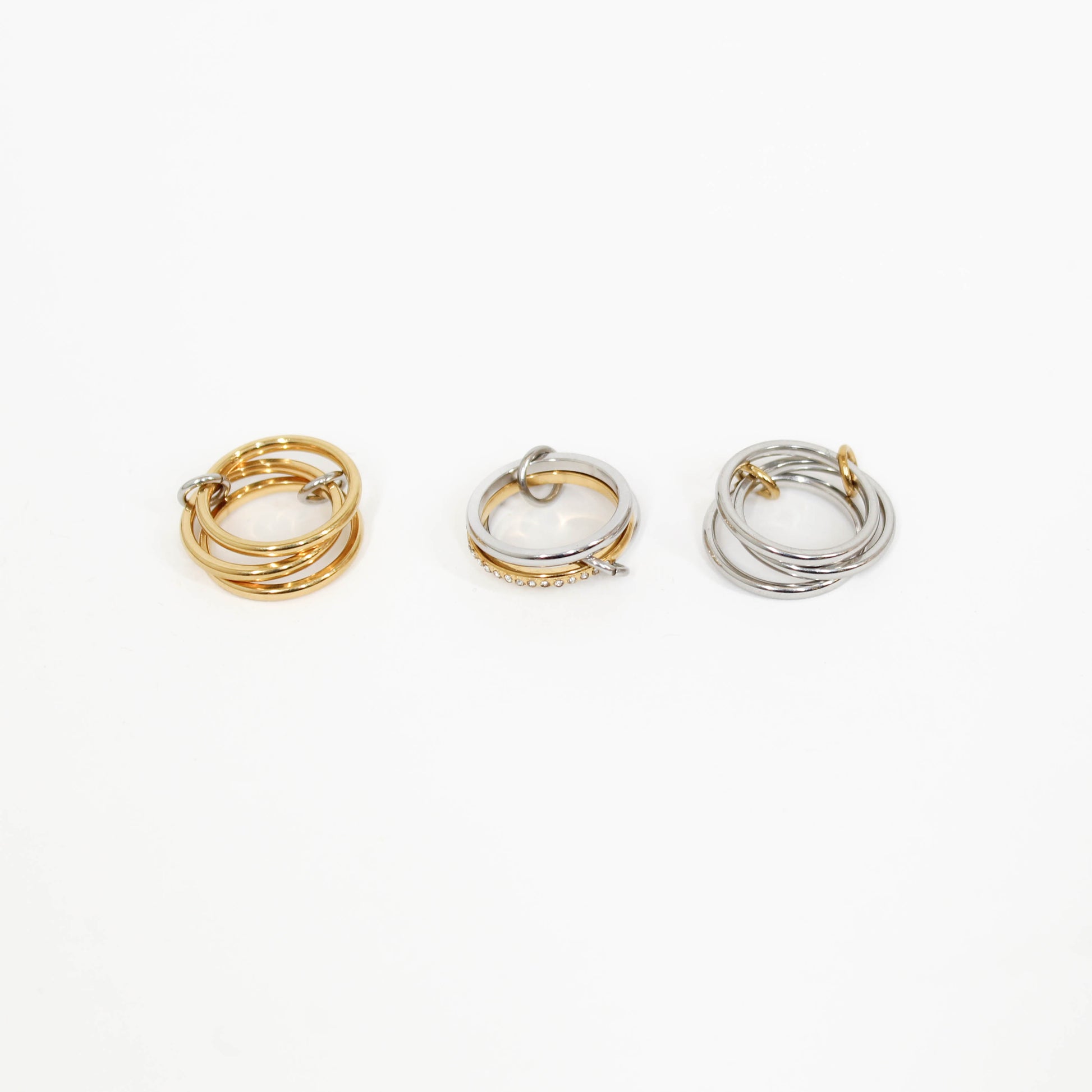 Three interlocking rings in gold, silver, and mixed metal on a white background