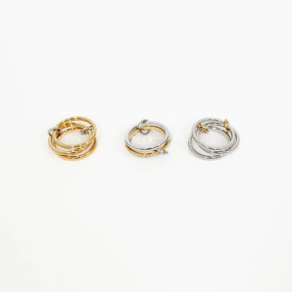 Three interlocking rings in gold, silver, and mixed metal on a white background
