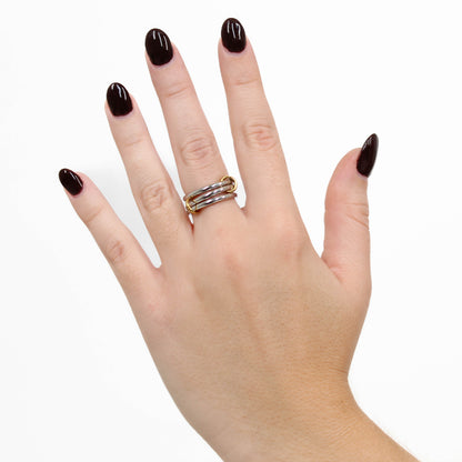 Hand wearing silver interlocking link ring on a white background