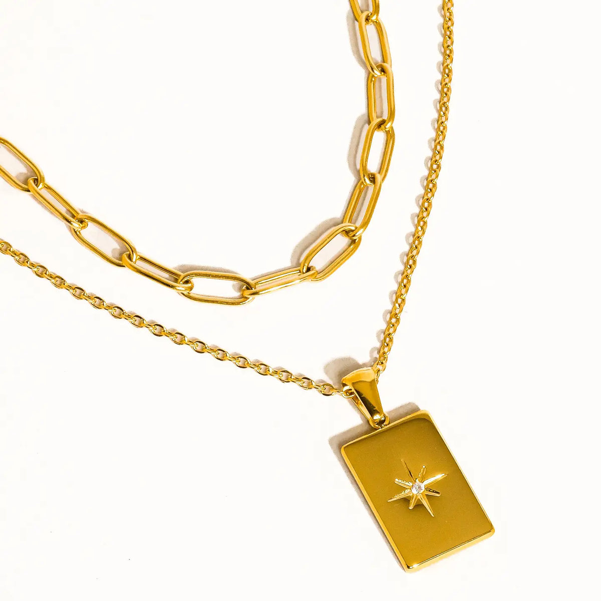 close up of two layered gold necklaces with one star pendant 