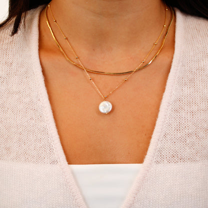 short gold necklace layered with gold necklace with pearl on model