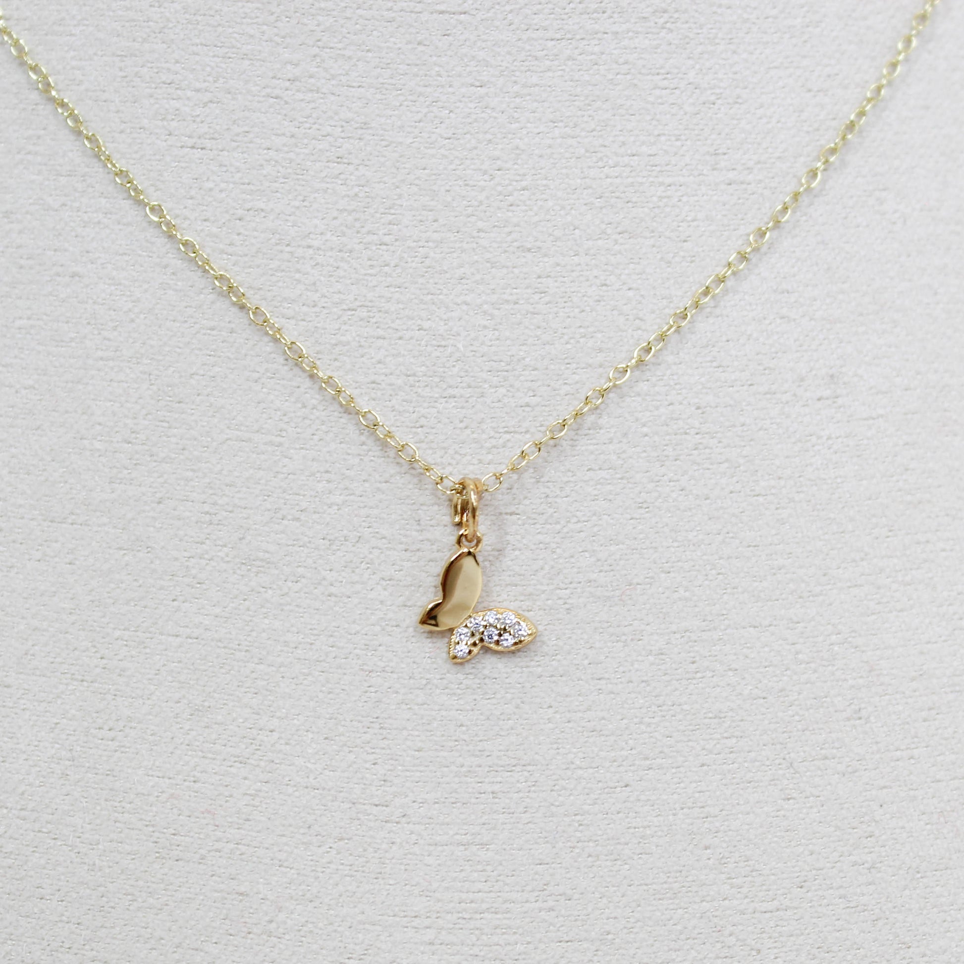Gold butterfly necklace with a small pendant on a white background