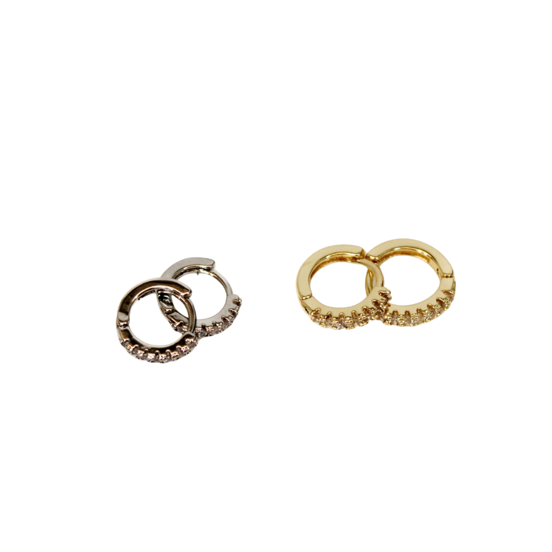 one pair of silver and one pair of gold Mini Huggie Hoop Earrings laying on flat white surface