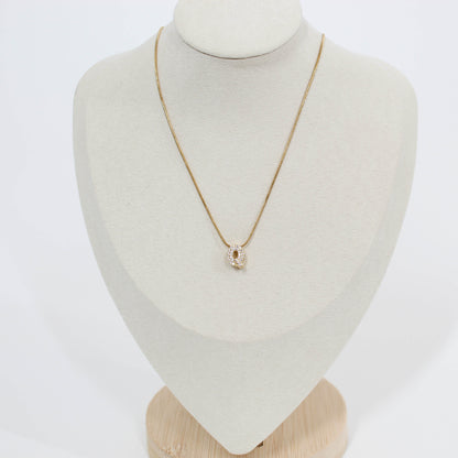 Gold necklace with a Q pendant on a mannequin bust against a white background