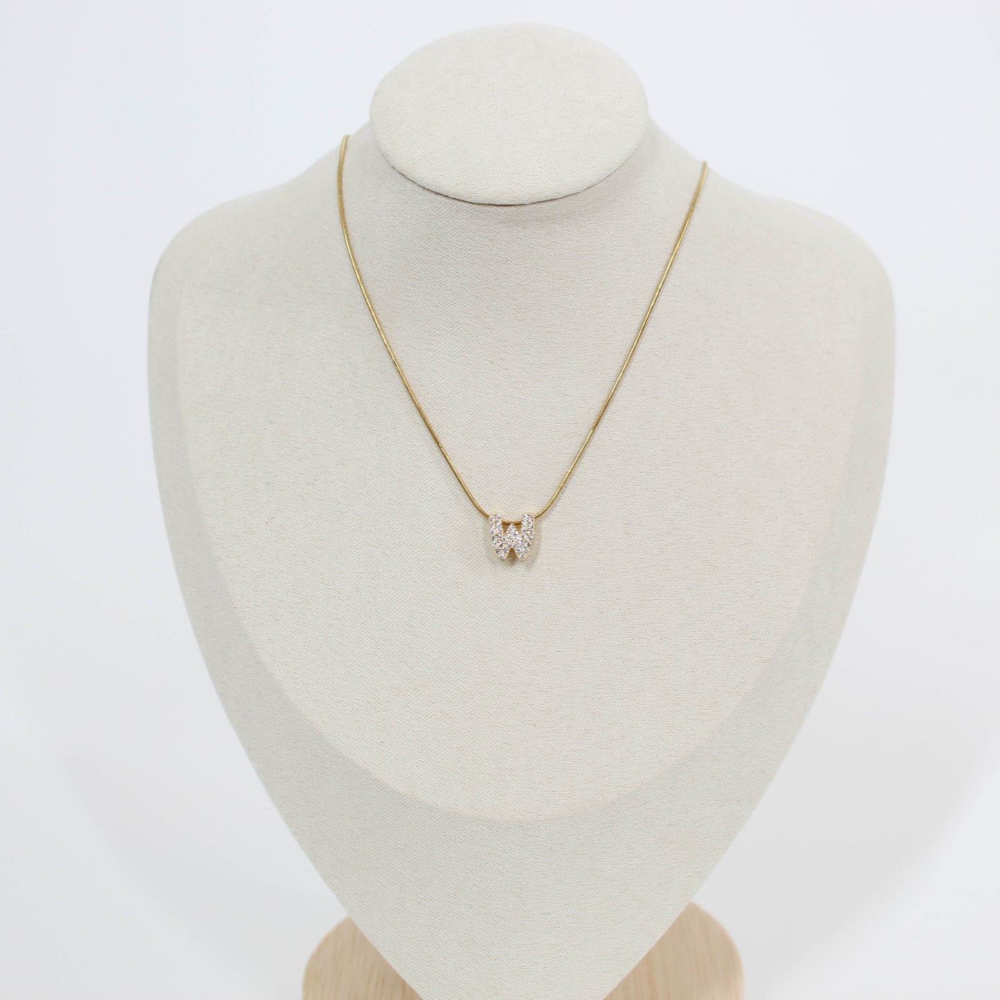 Gold necklace with a W pendant on a mannequin bust against a white background