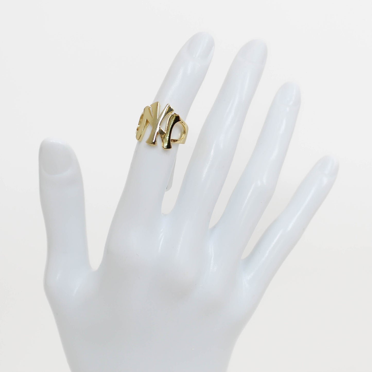 Gold NY Yankees ring on a white mannequin hand against a white background
