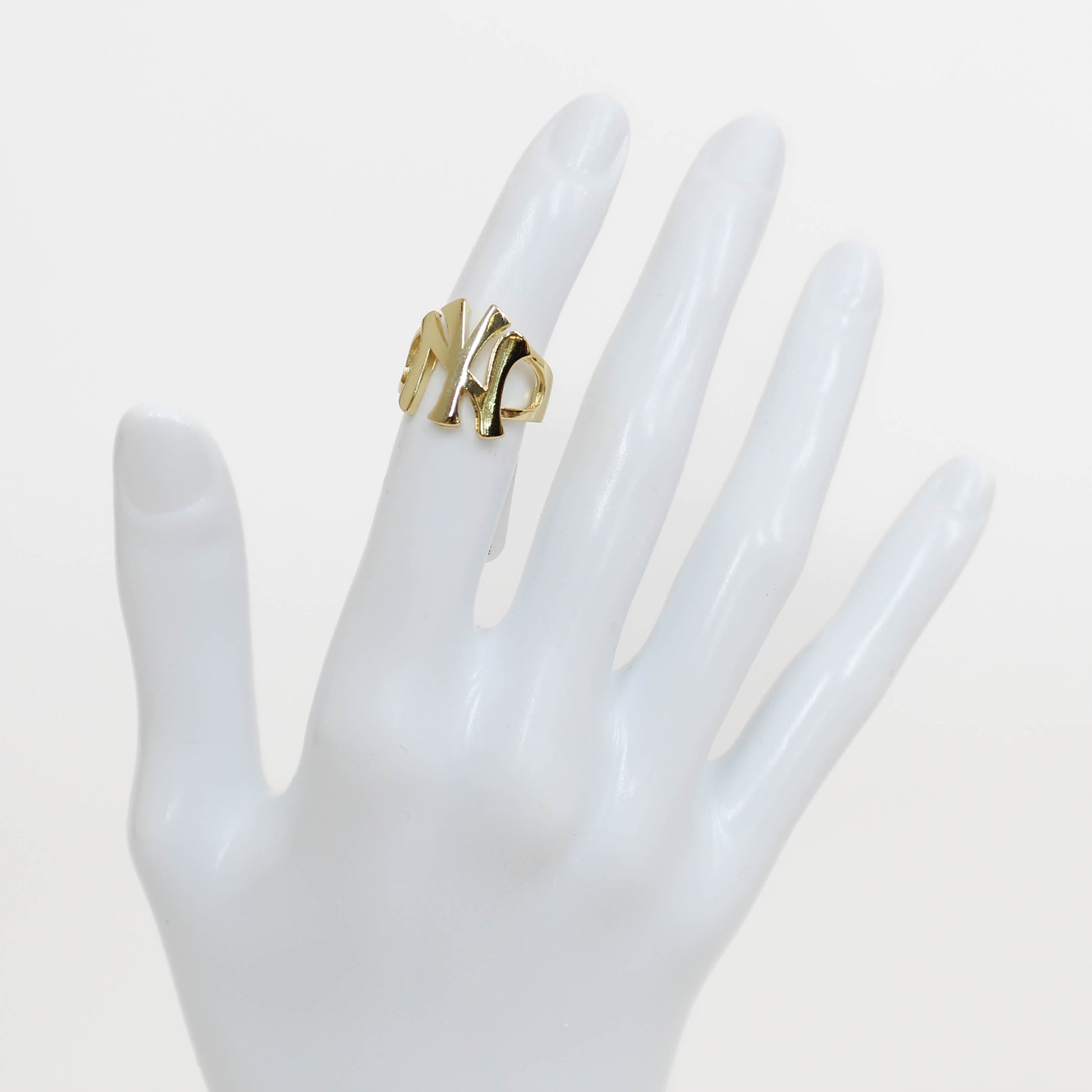 Gold NY Yankees ring on a white mannequin hand against a white background