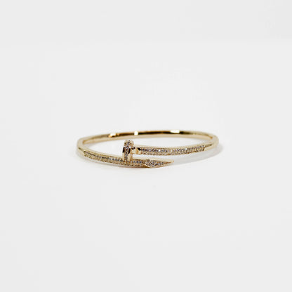 Gold nail bangle bracelet with small diamonds on a white background