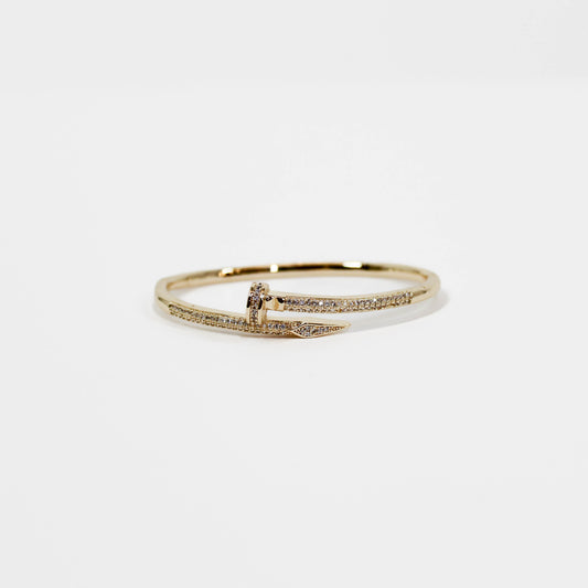 Gold nail bangle bracelet with small diamonds on a white background