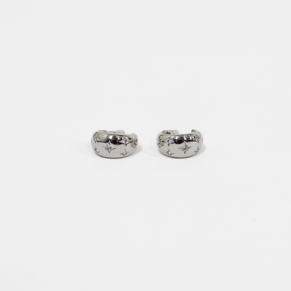 Pair of silver northern stars hoop earrings with embedded stones on a white background