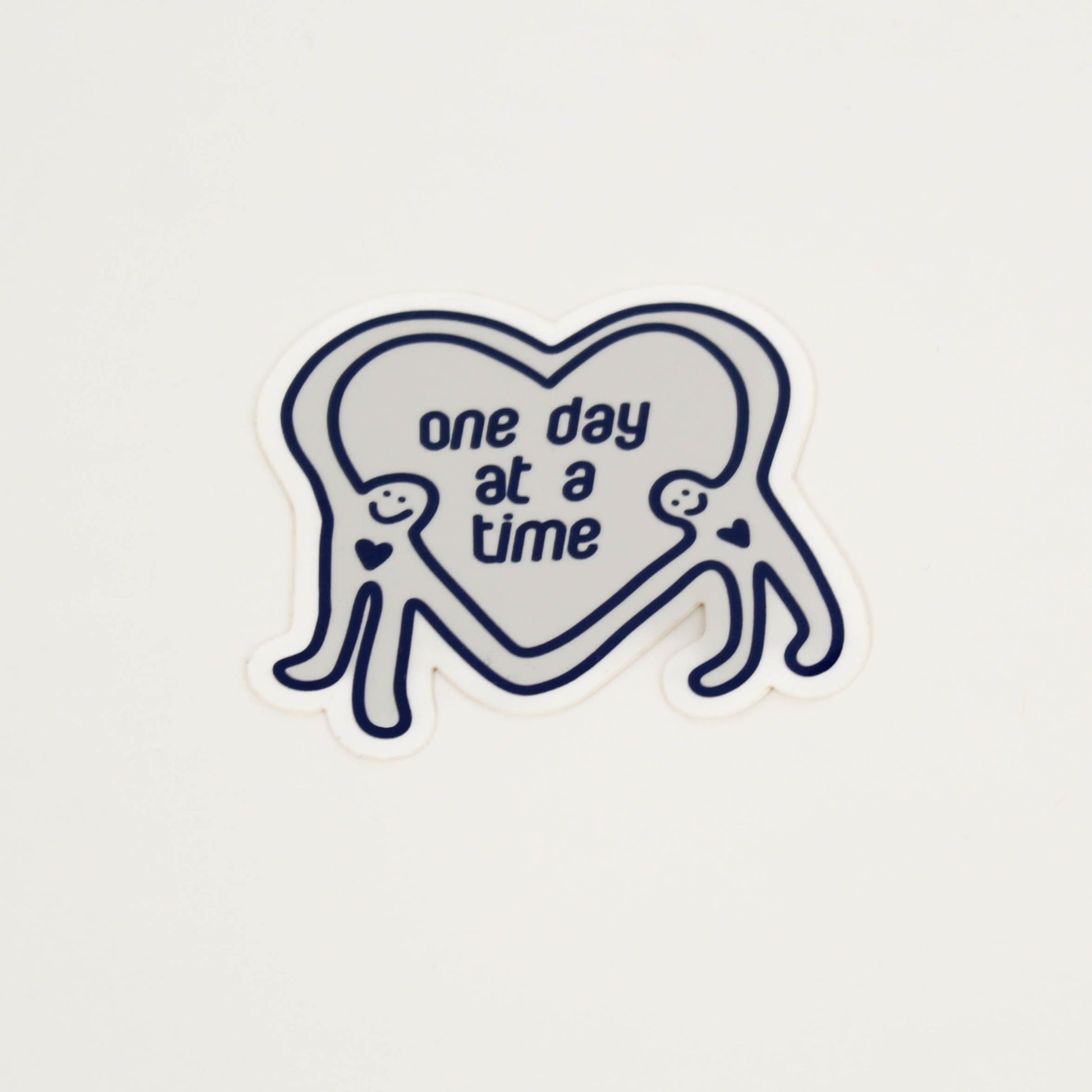 Heart-shaped sticker with 'one day at a time' text 