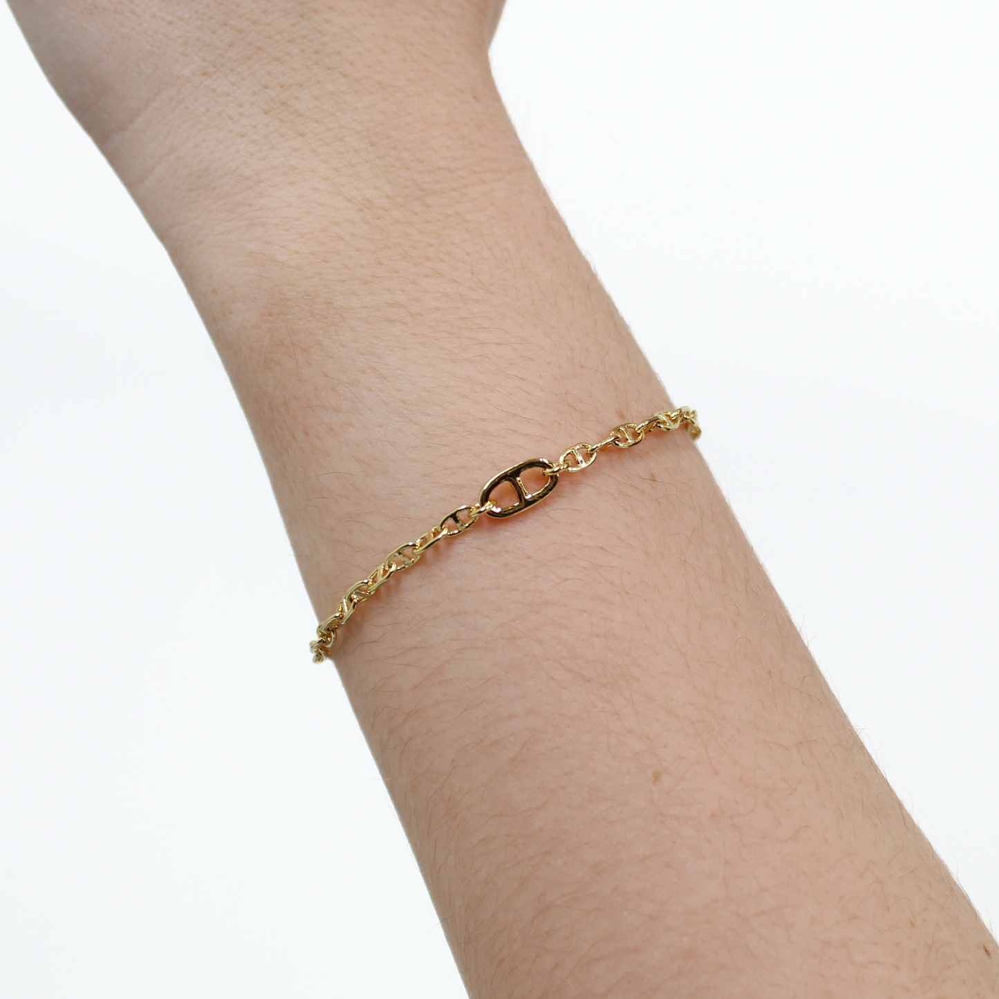 Gold oval link chain bracelet on a person's wrist against a white background
