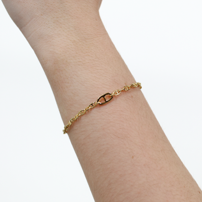 Gold oval link chain bracelet on a person's wrist against a white background
