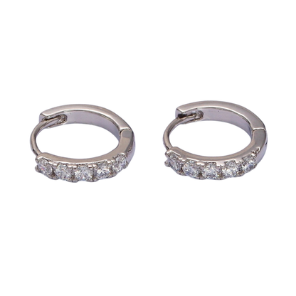 Pair of silver hoop pave huggie earrings with embedded stones on a white background