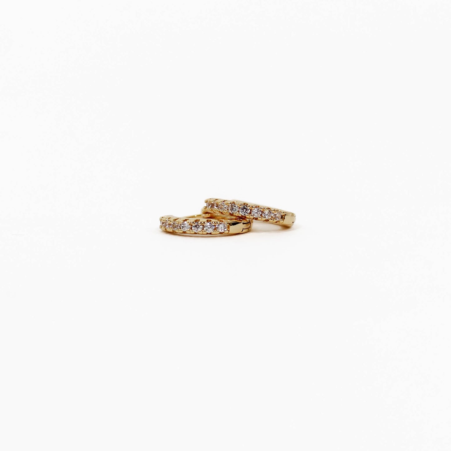 Two gold pave huggie earrings with diamond accents on a white background