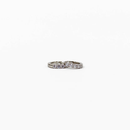 Silver pave huggie earrings with embedded stones on a white background