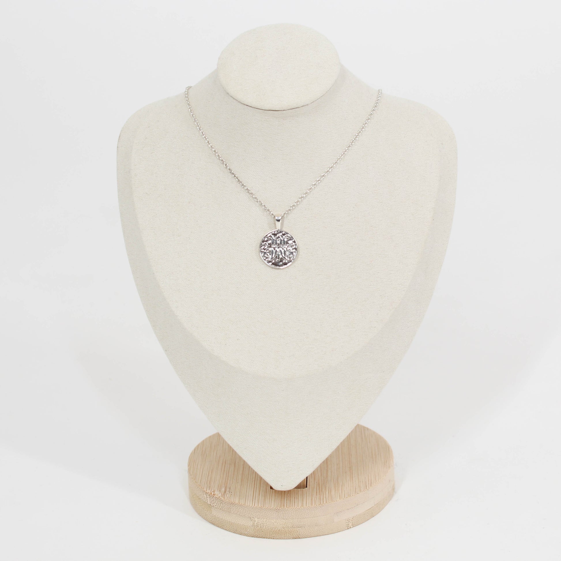 Necklace with a scripted M disc pendant necklace for Marist on a white mannequin bust