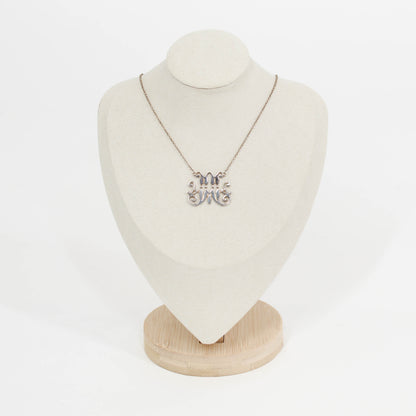 Necklace with a silver scripted M for Marist pendant on a mannequin bust against a white background