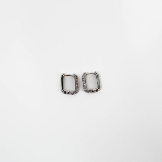 Two silver square huggie hoop earrings on a white background
