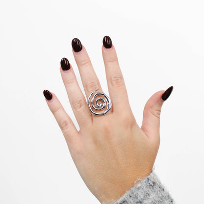 Hand wearing a silver spiral ring on a white background