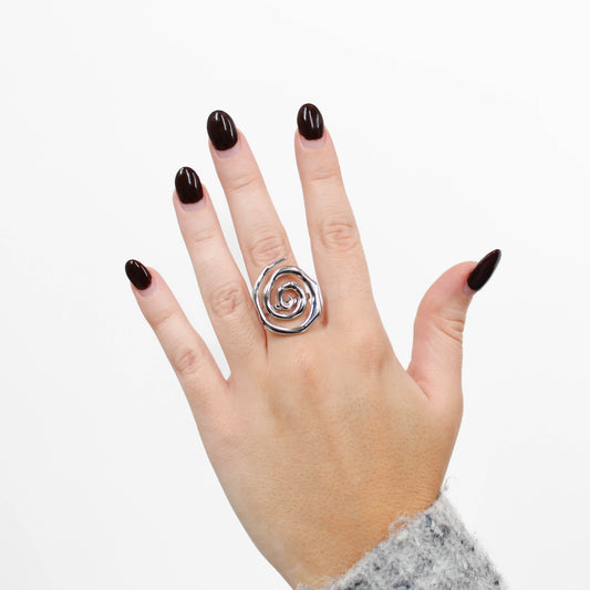 Hand wearing a silver spiral ring on a white background