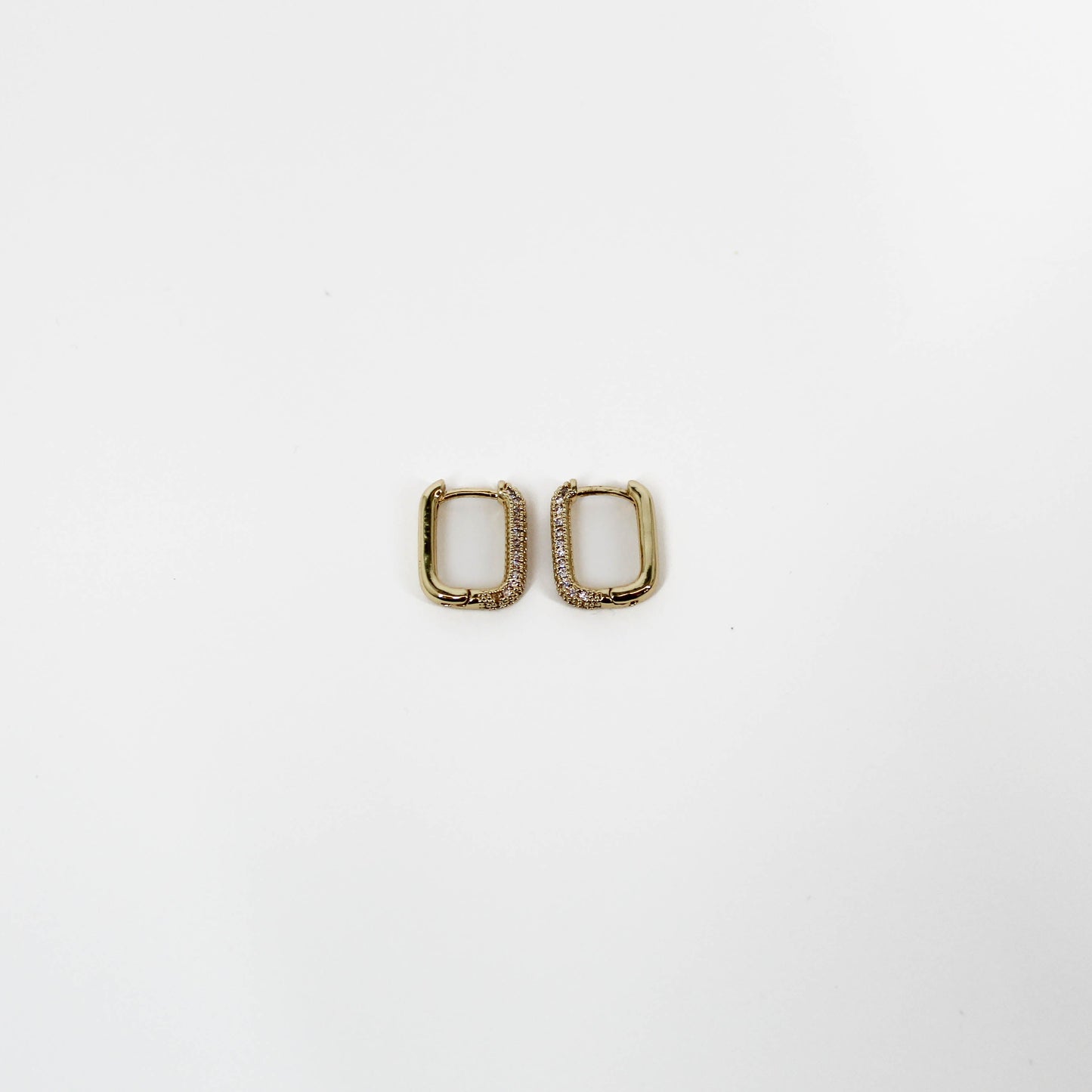 Gold square huggie hoop earrings with clear stones on a white background