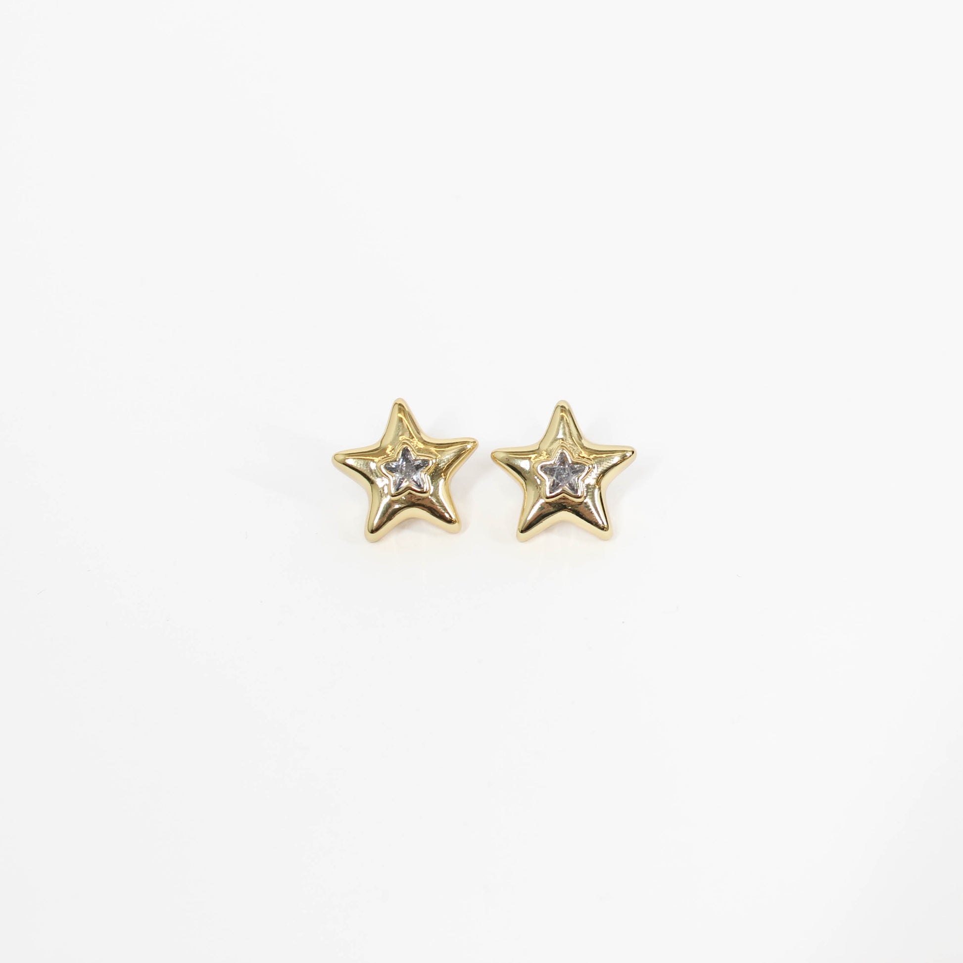 Gold star-shaped statement earrings with embedded stones on a white background