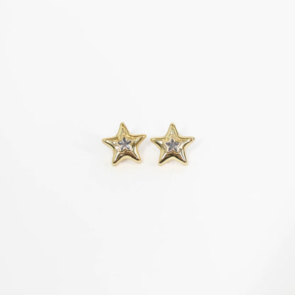 Gold star-shaped statement earrings with embedded stones on a white background