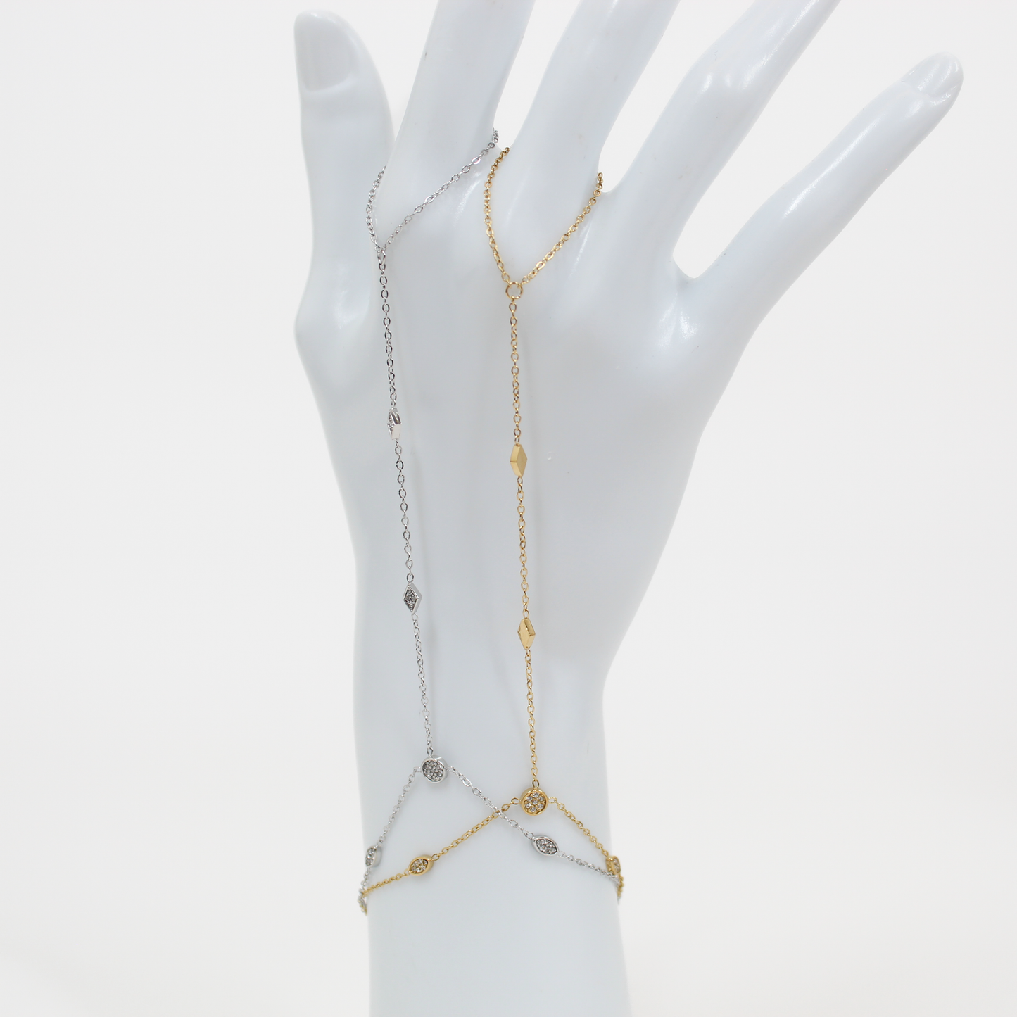 Gold and silver stone charm hand chain bracelet on a mannequin hand against a white background