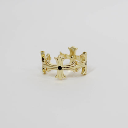 Gold cross ring with a black gemstone on a white background