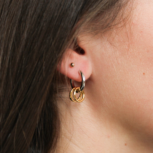 Close-up of an ear wearing a two tone link hoop earring. 