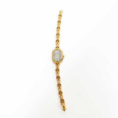 Gold vintage oval watch with a white face on a white background 