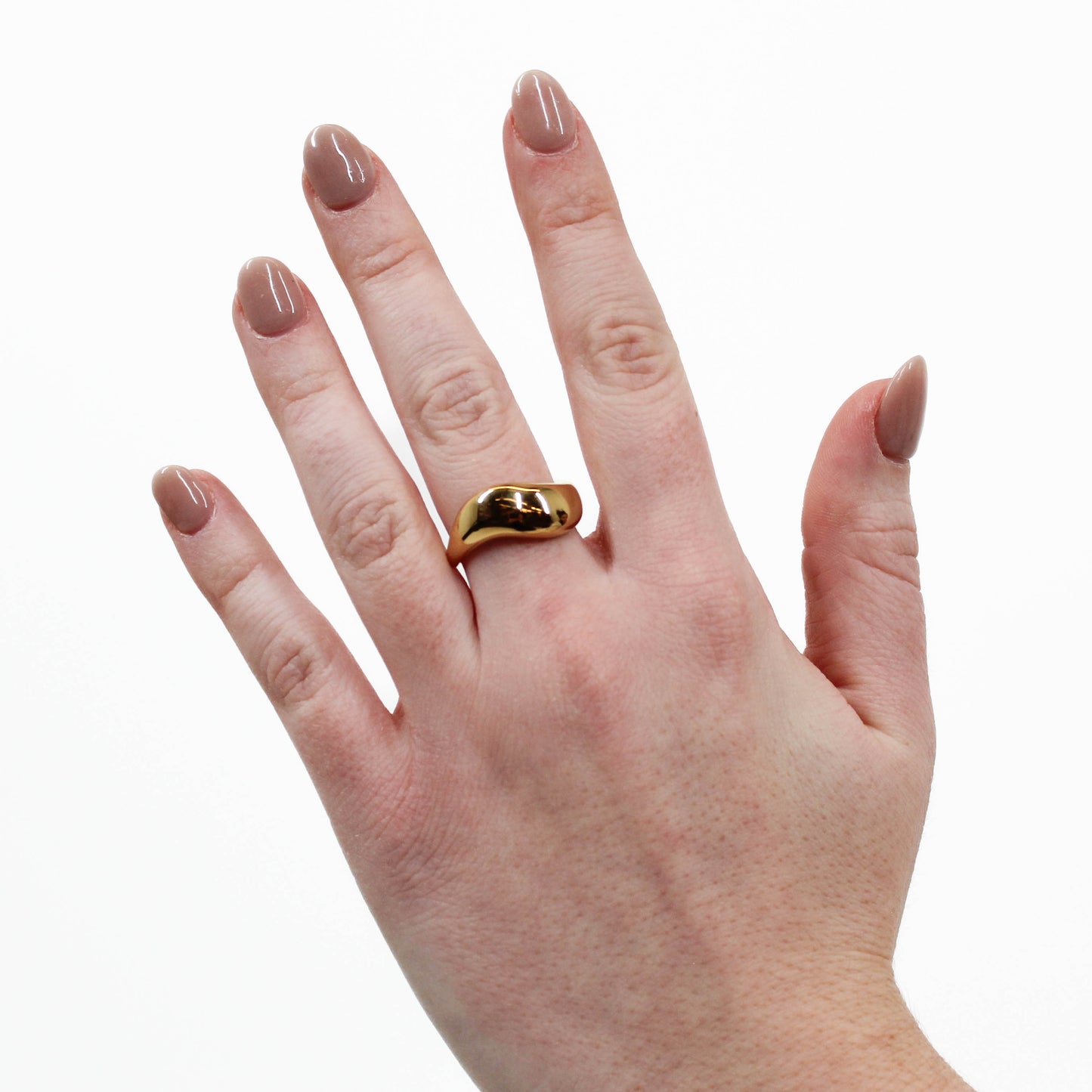Hand wearing a gold wavy ring on a white background
