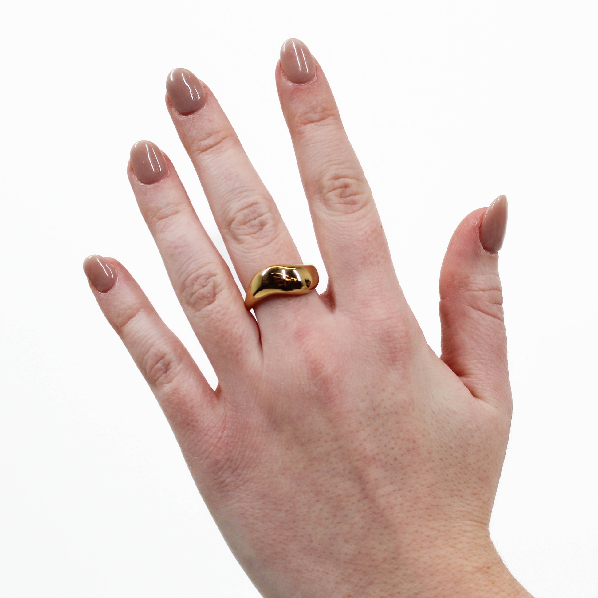 Hand wearing a gold wavy ring on a white background