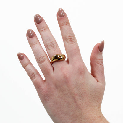 Hand wearing a gold wavy ring on a white background