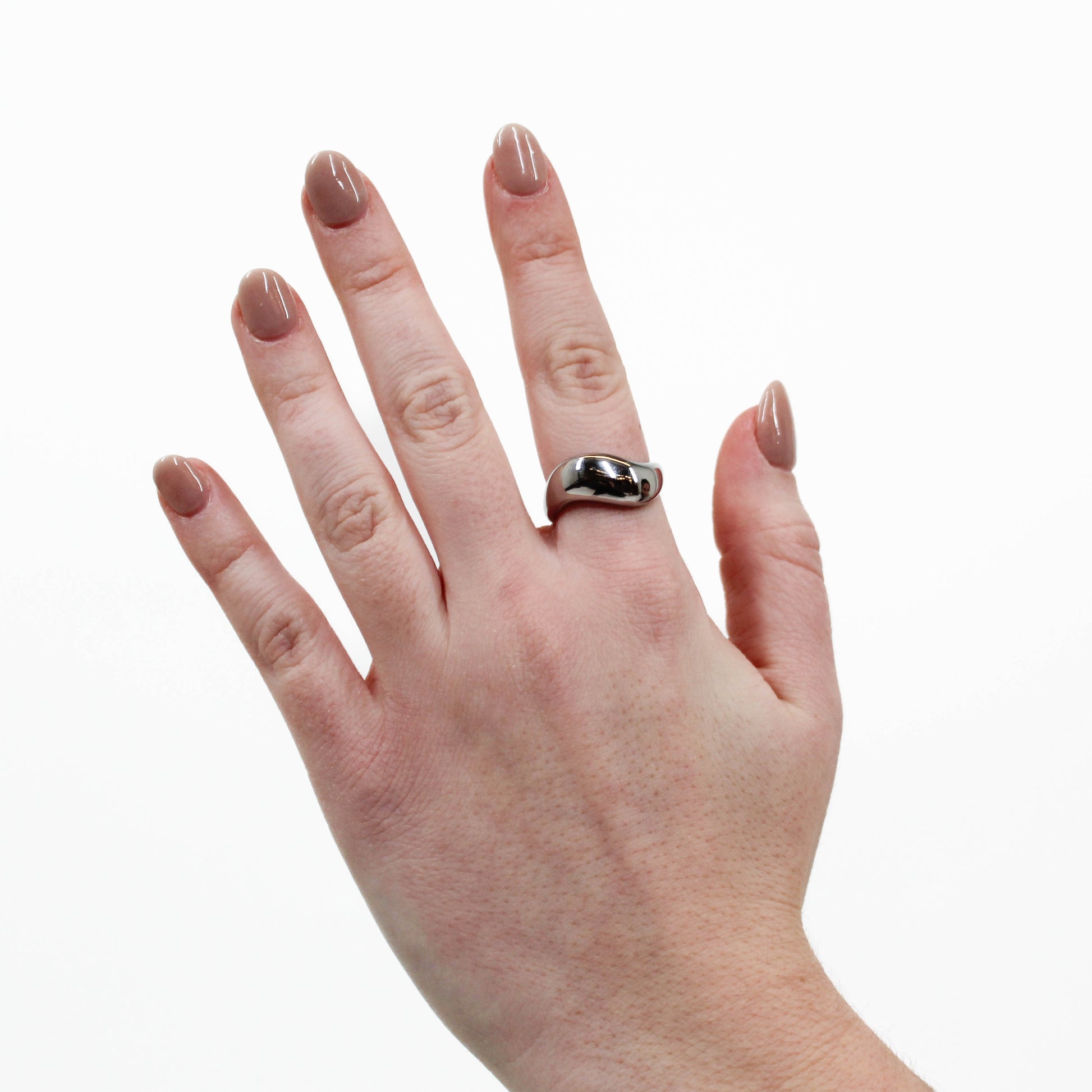 Hand wearing a silver wavy ring on a white background