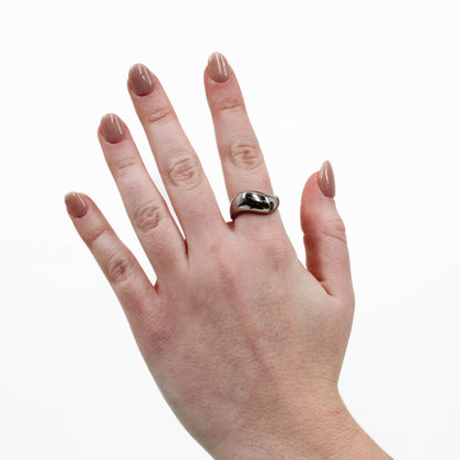 Hand wearing a silver wavy ring on a white background