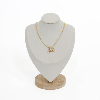 Gold yankee charm pendant necklace with a pretzel pendant on a white mannequin bust with a wooden base.
