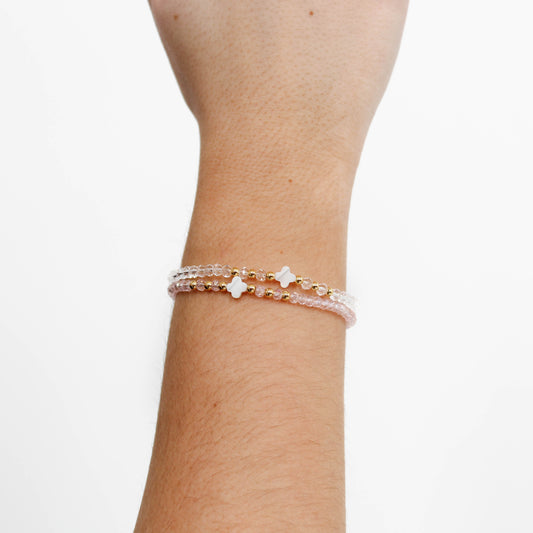 Stack of beaded crystal clover bracelets on a wrist against a white background