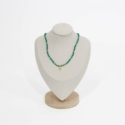 emerald beaded mini cross choker necklace on a white mannequin bust with a wooden base against a white background