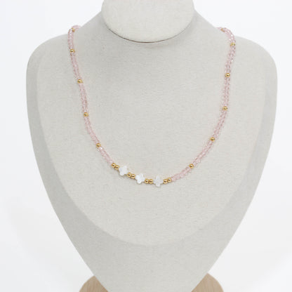 clover necklace with pink and gold beads on a mannequin bust against a white background