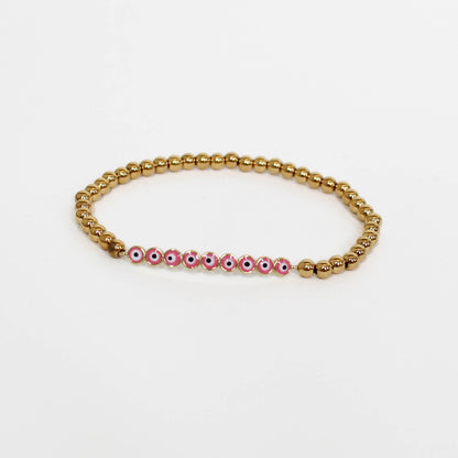 Bracelet with gold beads and pink beads with eye designs on a white background