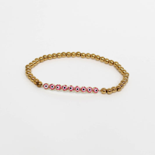 Bracelet with gold beads and pink beads with eye designs on a white background