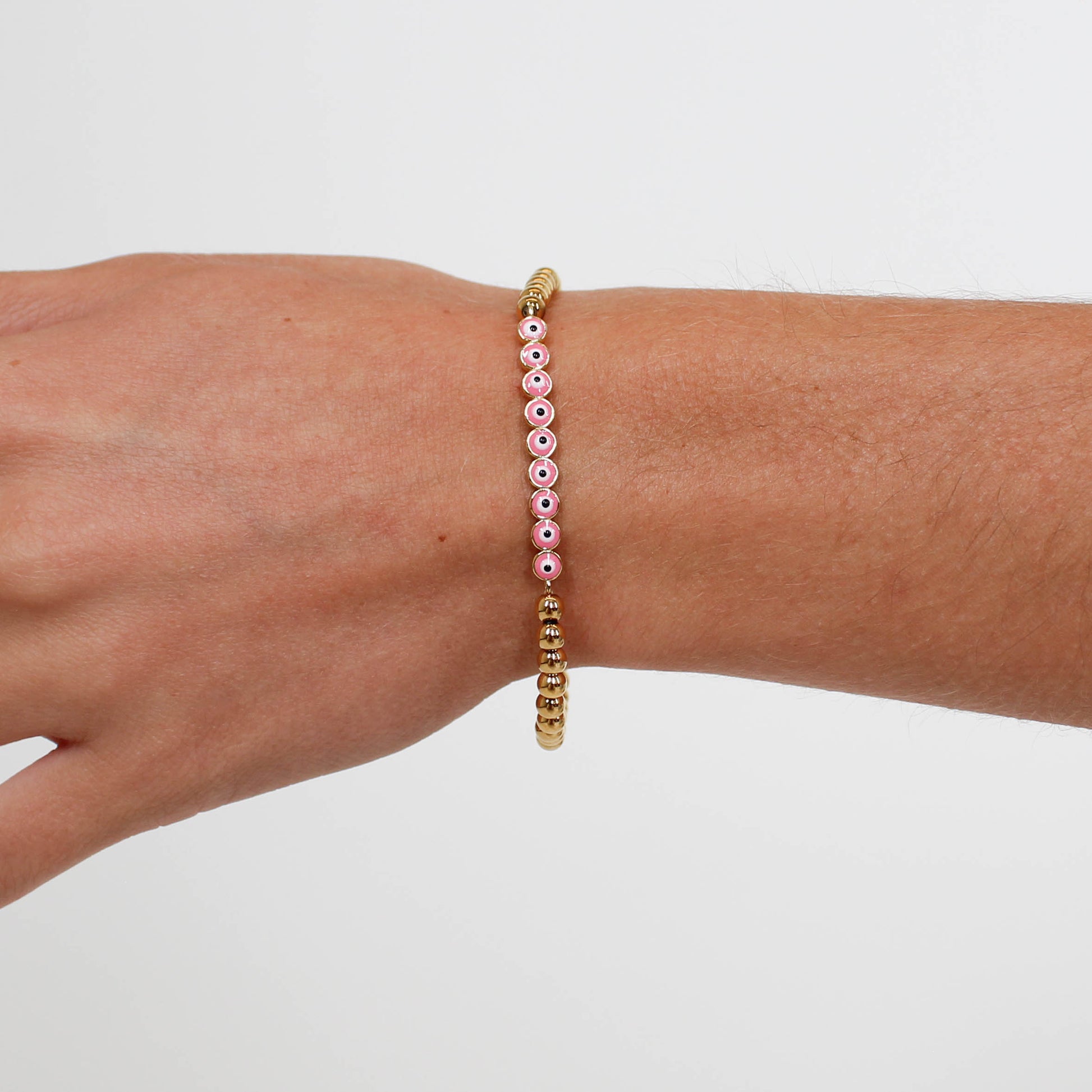 Bracelet with pink and gold beads on a wrist against a white background