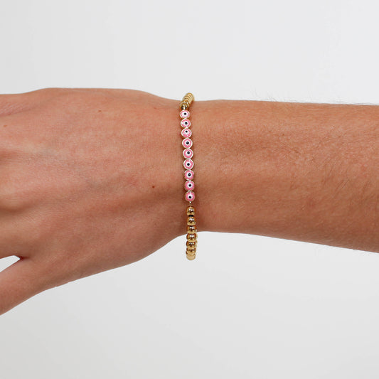 Bracelet with pink and gold beads on a wrist against a white background